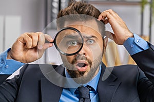 Business man holding magnifying glass near face, looking with big zoomed eye, searching, analysing