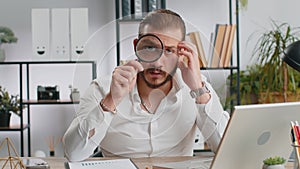 Business man holding magnifying glass near face, looking with big zoomed eye, searching, analysing