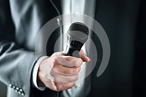 Business man holding microphone. Public speaking and giving speech in suit for audience concept.