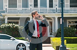 Business man holding mobile cell phone using app texting sms message wearing suit. Young urban professional man using