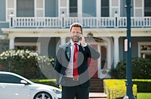 Business man holding mobile cell phone using app texting sms message wearing suit. Young urban professional man using