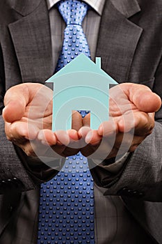 Business man holding a model of a house in his hands