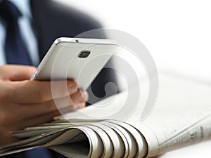 Business man holding a newspaper and a smart phone in his hand. The white background image