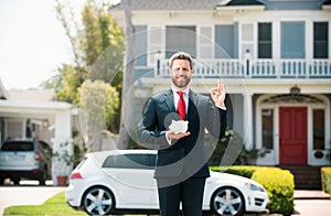 Business man holding piggy bank on home house background. Handsome caucasian man holding piggybank for money for savings