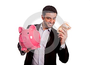 Business man holding pink piggy bank with money in hand