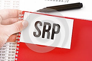 Business man holding a red notebook and white card with text srp. Financial concept