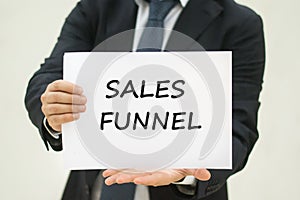 Business man holding Sales funnel TEXT on white sheet