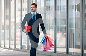 Business man holding shopping bags and walking in shopping store. Shopping and paying. Shopaholic shopping concept.