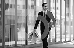 Business man holding shopping bags and walking in shopping store. Shopping and paying. Shopaholic shopping concept.