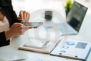 business man holding a smartphone and working on a laptop