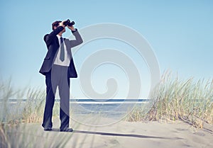 Business Man Holding Spyglass on Beach photo