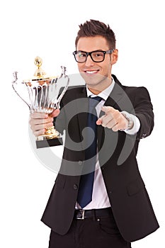 Business man holding a trophy and pointing