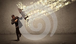 Business man holding umbrella against dollar rain concept