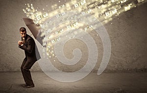 Business man holding umbrella against dollar rain concept