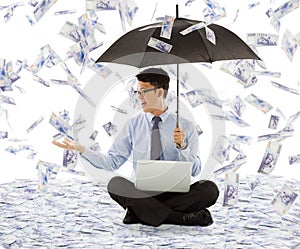 Business man holding a umbrella and catching money