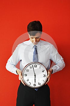Business man holding wall clock