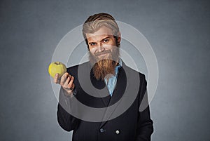 Business man holds one green apple and smiles