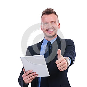 Business man holds tablet and shows thumb up