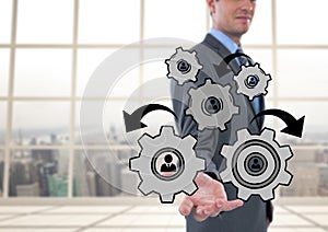 Business man interacting with people in cogs graphics against office background