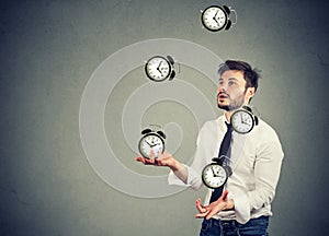 Business man juggling his time alarm clocks