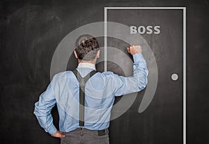 Business man knock by fist on boss door blackboard