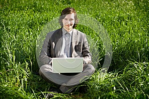 A business man with a laptop on the grass field
