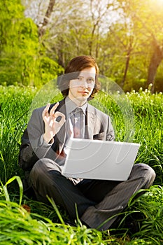 Business man with a laptop on the grass field