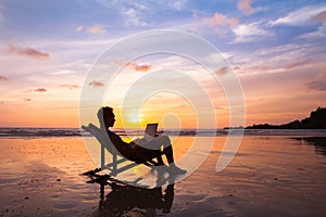 Business man with laptop working on the beach