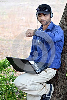 Business man listing to the music with laptop in a park