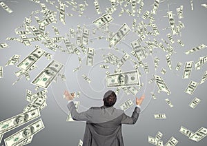 Business man looking at money rain against grey background
