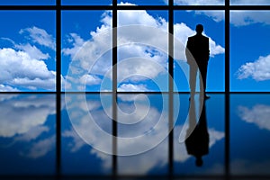 Business Man Looking Out of High Rise Office Window at Blue Sky and Clouds