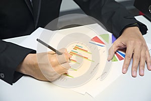 Business man looking and writing at business charts, graphs and documents background for analyzing the business