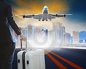 business man and luggage standing on airport runways with passenger jet plane flying above airport runway use for aircraft