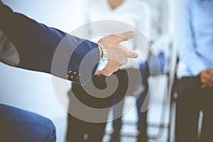 Business man making presentation to group of people, close-up. Speaker delivering a seminar to his colleagues or