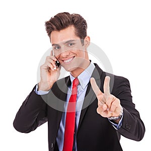 Business man making victory sign on phone