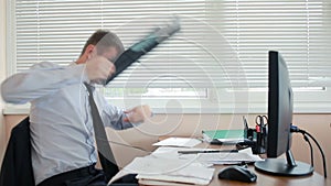 Business man, manager in anger smashes keyboard on desk, sitting in office