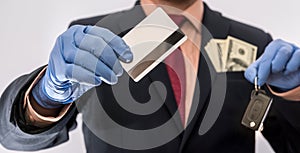 Business man in medical gloves holding credit card and car key, with money in poket, epidemic covi19 photo