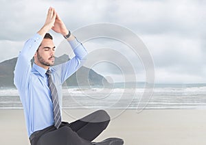 Business man meditating against blurry beach