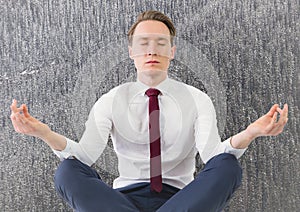 Business man meditating against grey trees