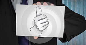 Business man mid section with card showing thumbs up doodle against blue wood panel