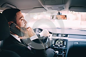Business Man with mobile phone while driving a car.
