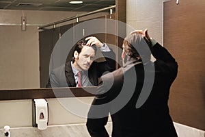 Worried Hispanic Business Man Looking At Hairline In Office Restrooms photo