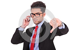 Business man on phone shows thumb down