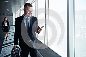 Business man, phone and travel in airport window for reading, thinking and contact in corridor with smile. Entrepreneur