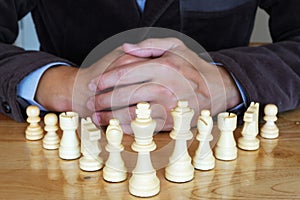 Business man playing chess game on wooden table. Business strategy analyzing concept.