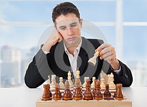 Business man playing chess, making the move