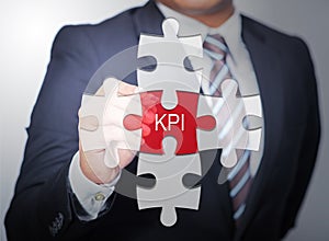 Business Man pointing on jigsaw written word KPI