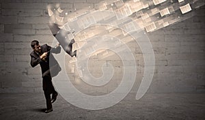 Business man protecting with umbrella against wind of papers