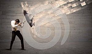 Business man protecting with umbrella against wind of papers