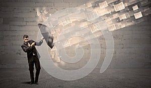 Business man protecting with umbrella against wind of papers